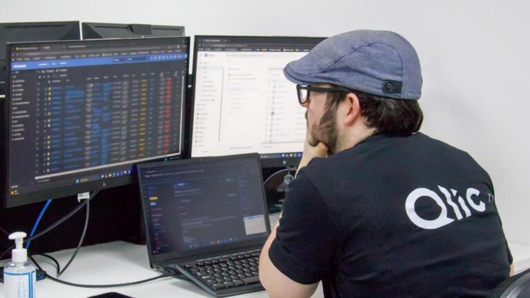 A Qlic IT engineer for charities reviewing multiple screens including a Microsoft Teams admin dashboard